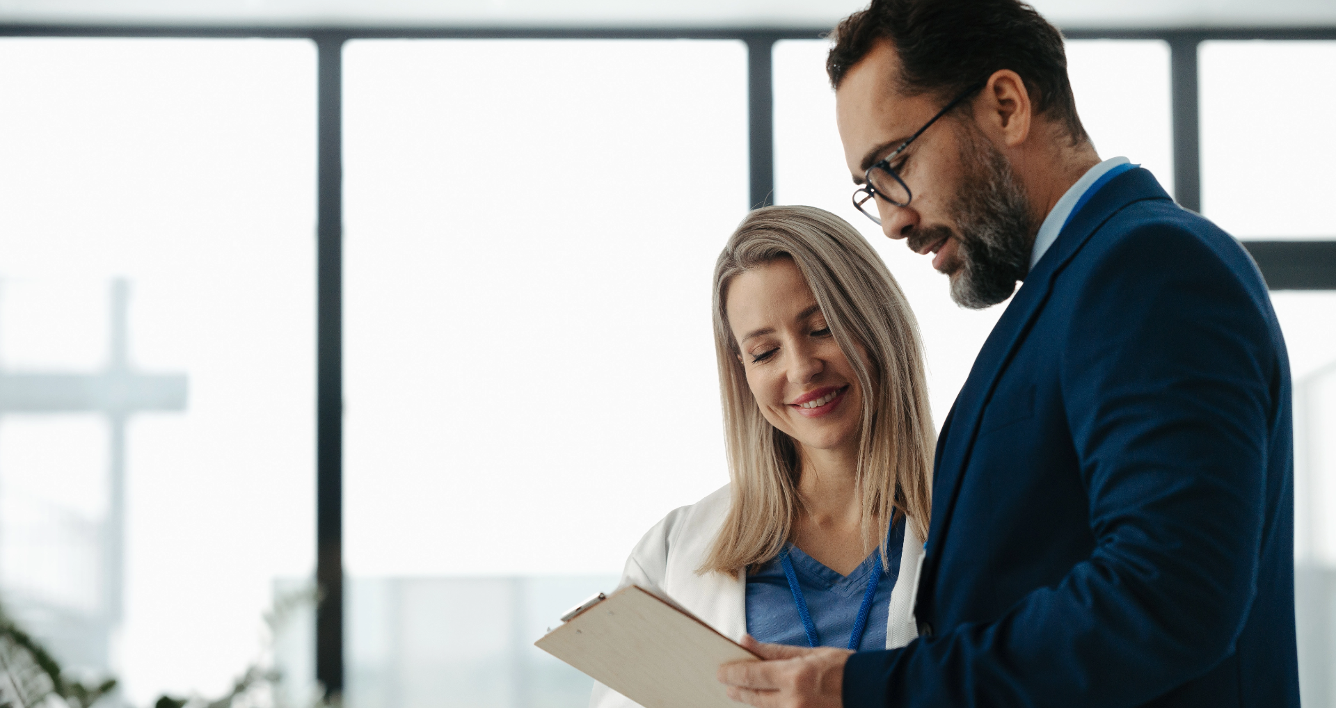 Male and female professionals talking over a clipboard