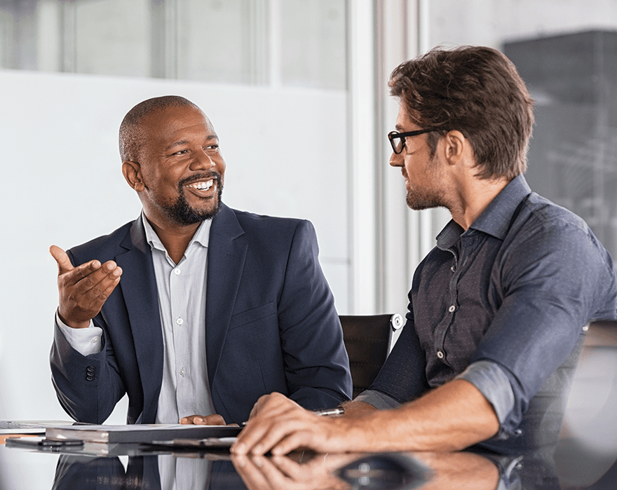 Two male businessmen at a table with documents talking